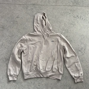 Beige hoodie med LOVE-tryck H&M Divided - Beige hoodie från H&M Divided med svart LOVE-tryck på bröstet. Tröjan har huva med snörning, ribbade muddar och är tillverkad i mjuk bomullsblandning med fleece på insidan. Perfekt för chill dagar och enkel att matcha med jeans eller joggers.