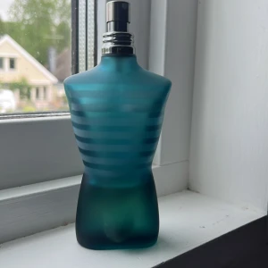 Jean Paul Gaultier Le Male parfym - 45 ml kvar i flaskan.Ikonisk parfymflaska formad som en manlig torso i frostat blågrönt glas med horisontella ränder. Metallisk spraytopp. En klassiker från Jean Paul Gaultier som sticker ut i badrumshyllan.
