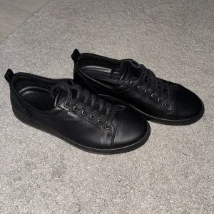 Svarta sneakers från Ecco i skinn - Stilrena svarta sneakers från Ecco med klassisk rund tå och snörning. Skorna är tillverkade i skinn och har GORE-TEX-membran som gör dem vattentäta. Perfekta för dig som vill ha en clean look och bekväma skor till vardags. Skorna är i mycket bra skick och de är använda en gång, det kan man se på skorna. De är väldigt bekväma, original priset är 1800kr. Storlek 36