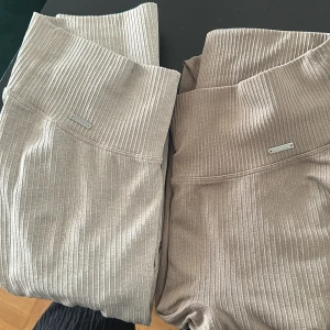 Ribbade leggings Aim'n i beige och grått - Två par ribbade leggings från Aim'n, ett par i ljusgrått och ett i beige. Hög midja och stretchigt material som sitter tight och bekvämt. Perfekta för träning eller chill, med diskret logga framtill.