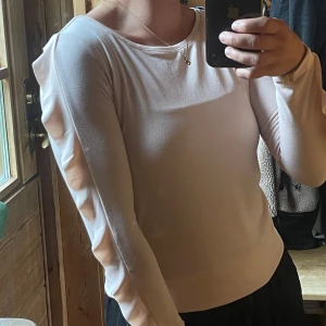 Ljusrosa långärmad topp med volang - Supersöt ljusrosa långärmad topp med volangdetaljer längs ärmarna.