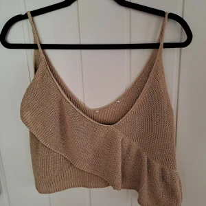 Zara croppad linnetopp - Säljer en beige stickad linnetopp med smala axelband och snygg volangdetalj framtill. Toppen är croppad och har en djup v-ringning, perfekt för varma dagar. Mjuk och luftig känsla tack vare det stickade materialet. Snygg Zara topp med volang, urringad, relativt kort modell i virkat. Passar till fest och vardag 🤩