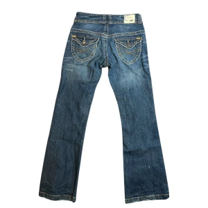 Lådmidjade bootcut jeans från Caterpillar - DÖsnygga jeans som har blivit för små (jag vill gråta). Köpta second hand i USA och är från märket CAT ”Caterpillar”. De är i superfint skick utöver lite slitage på benen (visas på sista bilden) som fanns redan när jag köpte dem. De har assnygga detaljer bak på fickorna och har 2 olika färger på sömmarna. Jag har tyvärr inga bilder med dem på men kan försöka skicka skärmdumpar från en video jag har om så önskas. Storlek: 32 Midjemått: 32cm Grenlängd: 19,5cm Benlängd: 75cm