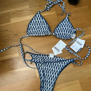 Blåvit mönstrad bikini från Subdued  - Supersnygg bikini från subdued i blått och vitt med ett unikt mönster. Triangeltopp med knyt i nacken och ryggen samt matchande trosa med smala band i sidorna. HELT NY, prislappar kvar