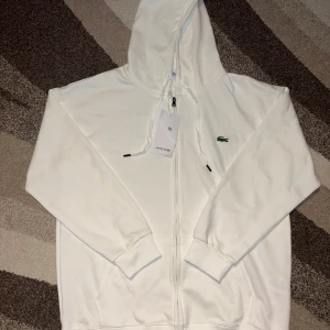 Lacoste Tracksuit - Hel Vit - Säljer nu min Tracksuit som aldrig använts.  Säljer den för att de inte passar min still. Storleken är XXL men är mer som XL. Vid frågor är det bara att skriva.