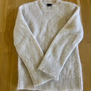 Beige stickad tröja från Lindex - Supermjuk och fluffig beige stickad tröja från Lindex i storlek S. Tröjan är gjord av 50% mohair och 50% ull, har rund halsringning och långa ärmar. Perfekt för lager-på-lager och ger en chill vibe till din outfit. Aldrig använd! Köpt för 2000kr