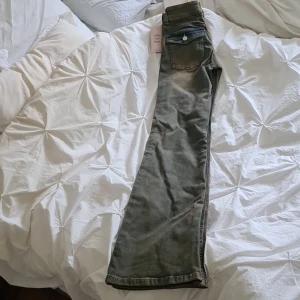 Brun/grå/blå bootcut jeans från Nelly - Snygga bootcut jeans från Nelly med dubbla knappar i midjan och coola bakfickor med lock och silverdetaljer. Jeansen har en klassisk femficksdesign och är tillverkade i mjukt denimtyg. Perfekta för dig som gillar en retro vibe och vill sticka ut. Jeansen är helt nya med lappar kvar, endast provade. Dottern fick dem i present, men var sugen på en annan modell, så dessa blev kvar oanvända. Nypris 699:-
