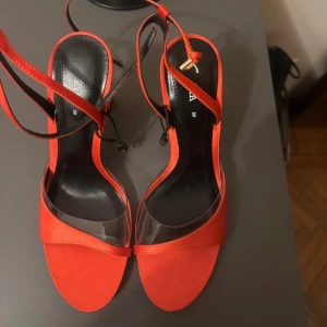 Röda klackskor från Zara - Snygga röda klackskor från Zara med transparenta detaljer och smala remmar. Perfekta för en kväll ute eller en speciell tillställning. Klacken ger en elegant touch och de är lätta att matcha med olika outfits.