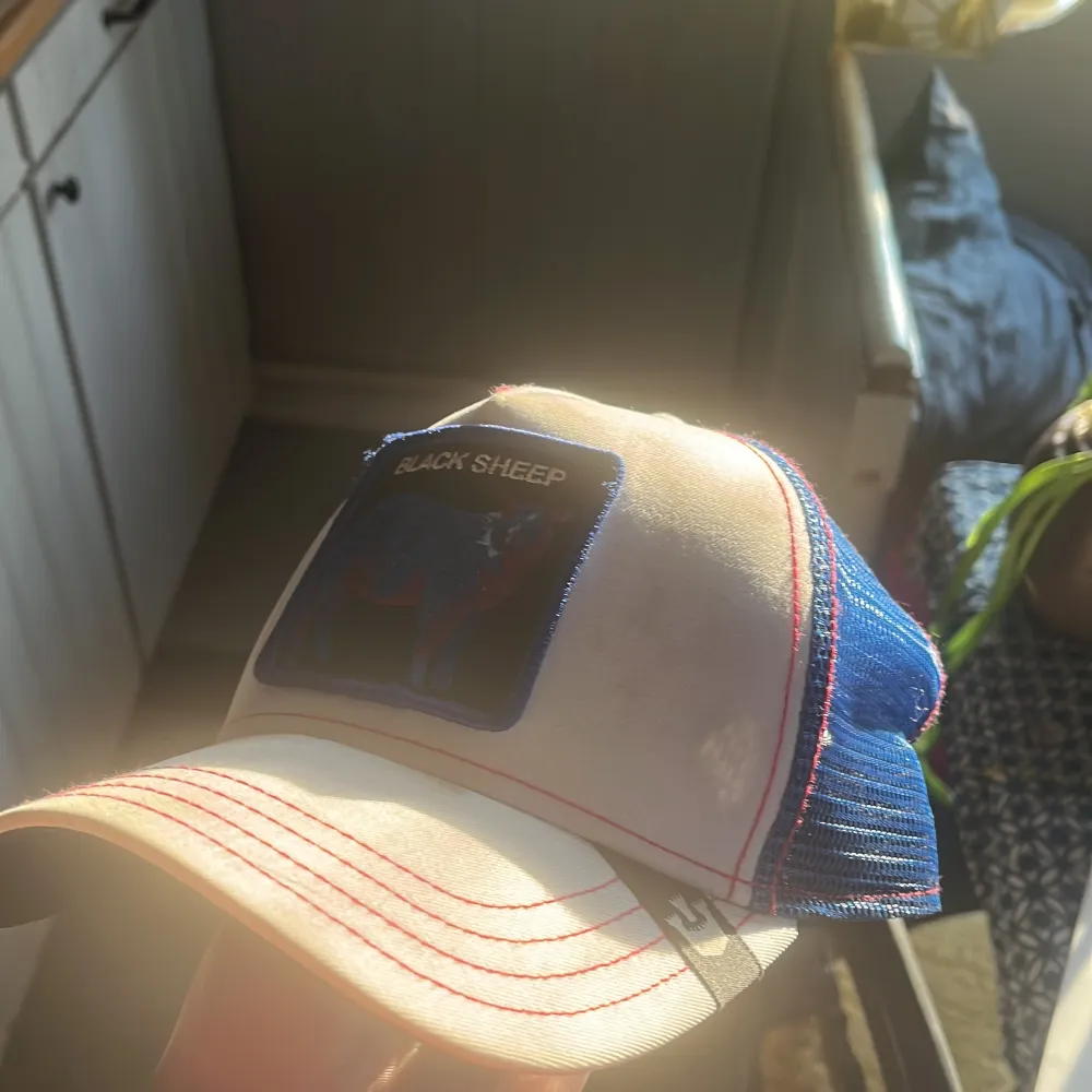 Snygg keps i vitt och blått med ett broderat 'Black Sheep' märke framtill. Kepsen har en böjd skärm och justerbar passform. Syns att den har använts men fortfarande fin.. Asusteet.