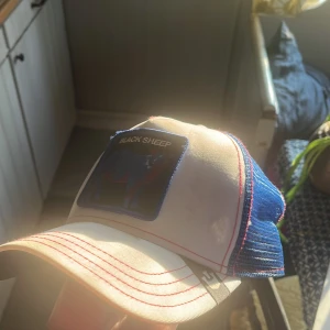 Goorin bros keps - Snygg keps i vitt och blått med ett broderat 'Black Sheep' märke framtill. Kepsen har en böjd skärm och justerbar passform. Syns att den har använts men fortfarande fin.