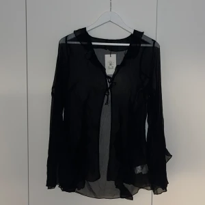 Genomskinlig blus - Genomskinlig blus men lite volanger från Bikbok.  Helt oanvänd. Nypris 359kr.