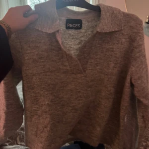 stickad tröja  - Säljer en stilren grå tröja från Pieces med krage och v-ringning. Perfekt för en avslappnad look. Tröjan har långa ärmar och är gjord i ett mjukt material. storlek m men sitter som xs/s