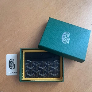 Svart plånbok - Säljer en svart plånbok med orange insida. Den är i nyskick och väldigt snygg. Kommer i original förpackning