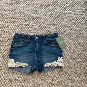 Jeansshorts med spetsdetaljer - Såå snygga blåa jeansshorts med vita spetsdetaljer. Aldrig använda med prislapp kvar❣️