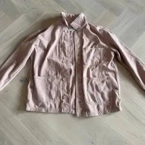 Säljer en stilren rosa jacka från Zara med knappar framtill och flera praktiska fickor. Jackan har en avslappnad passform och är perfekt för vår och höst. Den har långa ärmar och en klassisk krage.