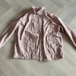 Rosa jeansjacka  - Säljer en stilren rosa jacka från Zara med knappar framtill och flera praktiska fickor. Jackan har en avslappnad passform och är perfekt för vår och höst. Den har långa ärmar och en klassisk krage.