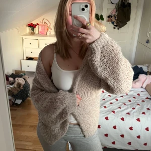 Beige stickad kofta - Mysig beige stickad kofta med långärmad design. Perfekt för kyligare dagar och ger en avslappnad look. Koftan har en lös passform och är gjord i ett mjukt material som känns skönt mot huden.