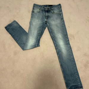 Blå jeans från Tiger of Sweden - Snygga blå jeans från Tiger of Sweden med en klassisk femficksdesign. De har en straight passform och är tillverkade i denim med en lätt tvättad look. Perfekta för en avslappnad stil.