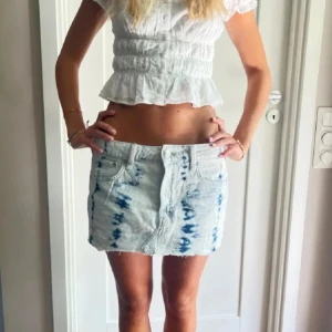 Lågmidjad Blå- och ljusblå mönstrad jeanskjol - Trendig kort jeanskjol med blå- och ljusblåt mönster. Kjolen har varit utsåld ett tag och går inte att få tag på. Den är vitt men blå sträck som lite tye die liknande och lågmidjad. Säljer pågrund av att den inte kommer till användning av mig och är k nyskick då den inte blivit använd. 