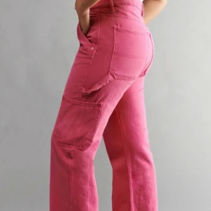 Rosa byxor från Sister - Snygga rosa byxor från Sister med hög midja och raka ben. Byxorna har praktiska fickor och stängs med dragkedja och knapp. Perfekta för en färgglad stil.Första byxorna är inte samma par men liknande då jag inte kunde hitta bild på just denna modellen.Köpta för ca 300-350kr,jag säljer de för 200