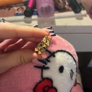 Guldfärgad ring med nitar - Snygg guldfärgad ring med nitar i ett geometriskt mönster. Perfekt för att ge en edgy touch till din stil. Passar bra till både vardag och speciella tillfällen. Ny pris 129