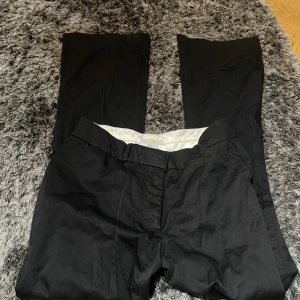 Svarta kostymbyxor - Snygga svarta kostymbyxor med en klassisk design. De har en rak passform och är perfekta för en stilren look. Byxorna har fickor både fram och bak, vilket ger en praktisk touch.