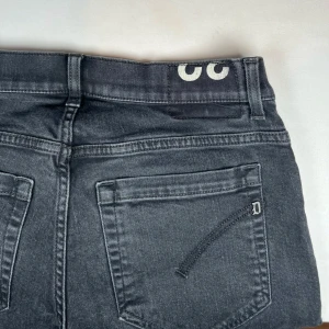 Svarta jeansbyxor från dondup - Snygga svarta jeansbyxor från dondup med en klassisk femficksdesign. Byxorna har en knappgylf och bälteshällor, vilket gör dem perfekta. Passformen är smal och de har en diskret logga på baksidan. W32/L34