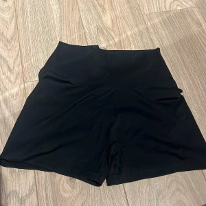 Svarta högmidjade shorts - Snygga svarta högmidjade shorts i ett stretchigt material. Perfekta för träning eller en avslappnad dag. De har en enkel design utan mönster eller detaljer, vilket gör dem lätta att matcha med olika toppar.