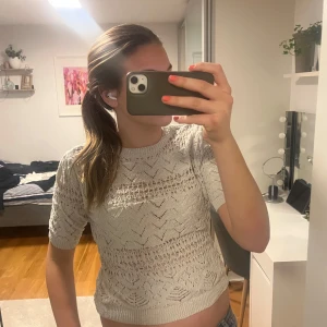 Vit stickad topp från Zara - Säljer en snygg vit stickad topp från Zara. Toppen har ett fint mönster och korta ärmar, perfekt för en stilren look. Den är croppad och passar bra till jeans eller kjol. Perfekt för vår och sommar!