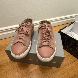 Rosa Axel Arigato - Snygga rosa sneakers i mocka med snörning och vit sula. Perfekta för en avslappnad stil med en touch av färg. De har en rund tå och är bekväma för vardagsbruk.