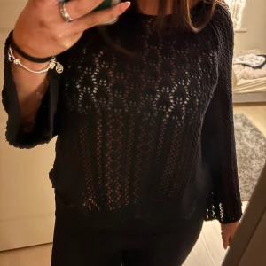 Svart stickad tröja - Säljer en snygg svart stickad tröja med ett vackert hålmönster. Tröjan har långa ärmar och en bekväm passform. Perfekt för att lägga till en stilfull touch till din outfit. Hör av dig vid intresse!