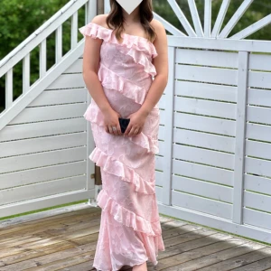 Rosa balklänning med volanger - Superfin rosa balklänning med volanger!! Of-shoulder med ett blommigt mönster 🌸 Den är endast använd ett fåtal gånger så den är i bra skick!! Den är i storlek 40 men passar mig perfekt som brukar ha 36/S. Tveka inte på att höra av dig om du har frågor 🌸