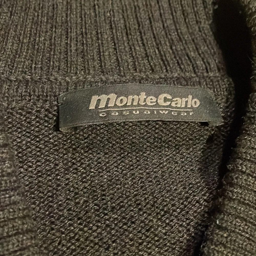 Snygg svart och grå cardigan från Monte Carlo med randigt mönster framtill. Jackan har en dragkedja och ribbade muddar vid ärmslut och nederkant. Perfekt för en stilren look!. Neuleet.