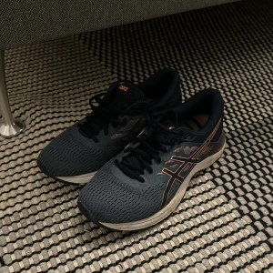 Svarta löparskor från Asics - Säljer ett par svarta löparskor från Asics med snygga orange detaljer. Hör av er vid intresse! Pris går att diskutera vid snabb affär!!