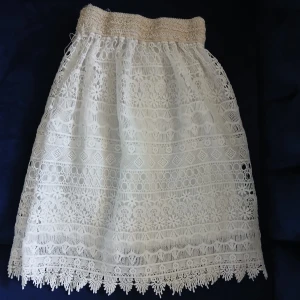 Vit spetskjol med volangkant - Superfin vit kjol med vacker spets och volangkant nertill. Kjolen har elastisk midja och ett detaljerat spetsmönster som ger en romantisk vibe. Perfekt för sommarens alla tillfällen!