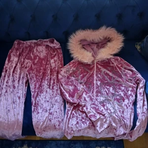 Rosa sammetstracksuit med fuskpäls🎀 - Säljer en rosa sammetstracksuit från Maxdunya i storlek XL men passar för de som har M också. Setet består av en hoodie med ljusrosa fuskpäls runt luvan🩷 glittriga stenar i geometriska mönster och dragkedja med gitarrhänge. Matchande byxor med resår och knytband i midjan💎