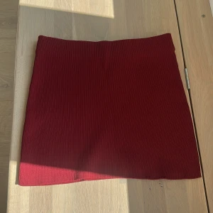 Ribbad vinröd kjol från Zara XS - Säljer en ribbad vinröd kortkjol från Zara i storlek XS. Kjolen har en tight passform och är tillverkad i ett stretchigt material som sitter snyggt. Perfekt att styla med en oversized tröja eller crop top för en trendig look.
