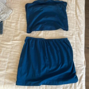 Blå kortkjol o topp  - Säljer en enkel och snygg blå kortkjol och topp. Kjolen har resår i midjan och en rak, klassisk passform som är lätt att matcha med olika toppar. Perfekt för dig som gillar en clean och stilren look. Passar xs o s