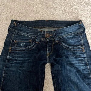 Lågmidjade Pepe jeans - Lågmidjade utsvängda Pepe Jeans i storlek W26 L34. Bra skick förutom att de är slitna bak längst ner på benet (se bild).   Midjemåttet: 36cm innerbenslängd: 81cm fotbredd: 22cm
