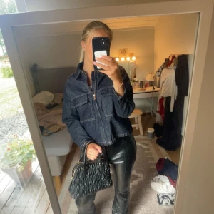 Mörkblå jeansjacka med dragkedja - Snygg mörkblå jeansjacka med dragkedja framtill och två stora bröstfickor. Jackan har en rak, lite boxig passform och klassisk krage. Perfekt att slänga över en t-shirt för en cool och avslappnad look.