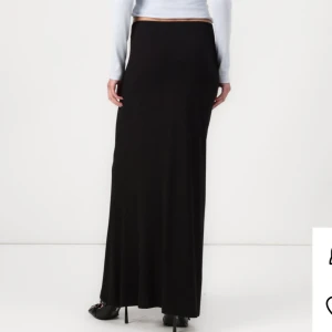 Svart långkjol i mjukt material - En svart långkjol med tight passform och enkel, stilren design. Kjolen är i ett mjukt och stretchigt material som sitter snyggt på kroppen och har en hög midja. Perfekt att styla med crop tops eller stickade tröjor. Endast TESTAD! Så den är i nytt skick!❤️köptes för 400kr!
