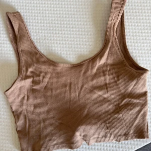 Beige ribbad linnetopp Gina Tricot - Säljer en beige ribbad linnetopp från Gina Tricot i storlek S. Toppen är ärmlös med breda axelband och har en croppad passform.