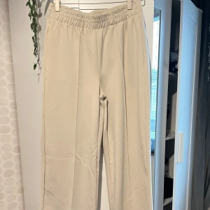 Beige mjukisbyxor med resårmidja - Snygga beige mjukisbyxor med bred resår i midjan och raka ben i storlek S. Byxorna köpte jag utomlands så jag har ingen aning vart de är ifrån men de har en avslappnad/baggy passform och är tillverkade i mjukt material som känns skönt mot huden. Perfekta för chill dagar eller när du vill vara bekväm men ändå se fräsch ut. Aldrig använt sen jag köpte den i april.