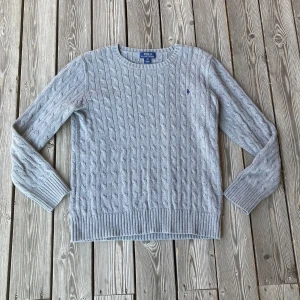 Grå kabelstickad tröja Polo Ralph Lauren - Grå kabelstickad tröja från Ralph Laure i mycket bra skick! Tröjan är i storlek 18-20 ungdom, men passar typ 175-180 eller S i herrstorlek. Passar perfekt till en vanlig outfit eller som övertröja till skjorta, hör av er om frågor!