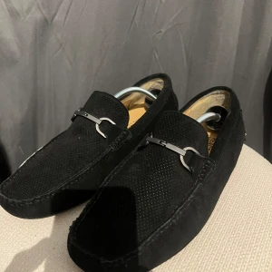 Svarta mockaloafers med metallspänne - Stilrena svarta loafers i mocka från 