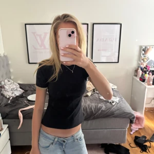 Svart topp med guldiga ärmslut från Zara - Svart kortärmad topp från Zara med snygga guldiga detaljer vid ärmsluten. Modellen är figurnära och croppad, perfekt till jeans eller kjol. Enkel men ändå med en twist tack vare de glittriga ärmsluten.