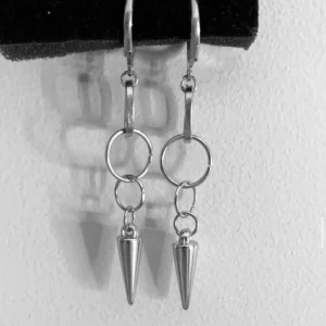 Silvriga örhängen med konformad detalj - Coola silvriga örhängen med två ringar och en hängande konformad detalj längst ner. De har en modern och edgy vibe, perfekta för att lyfta din stil. Passar dig som gillar unika accessoarer med attityd.