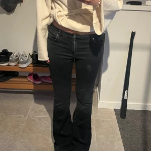 Svarta bootcut jeans - Snygga svarta jeans med bootcut-modell och klassisk femficksdesign. Jeansen har en låg midja och är tillverkade i stretchigt denimtyg som sitter skönt. Perfekta för dig som gillar en tidlös look med lite utsvängda ben. Storlek M, längd 31.