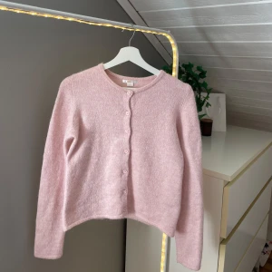 Ljusrosa kofta från Gina Tricot - Ljusrosa kofta från Gina Tricot med rund halsringning och knappar framtill. Storlek 158/164