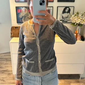 Grå kofta med knappar och fickor - Mysig grå kofta med ljusare ribbade kanter, knäppning framtill och två små fickor. Kashmir liknande material, superskön! 